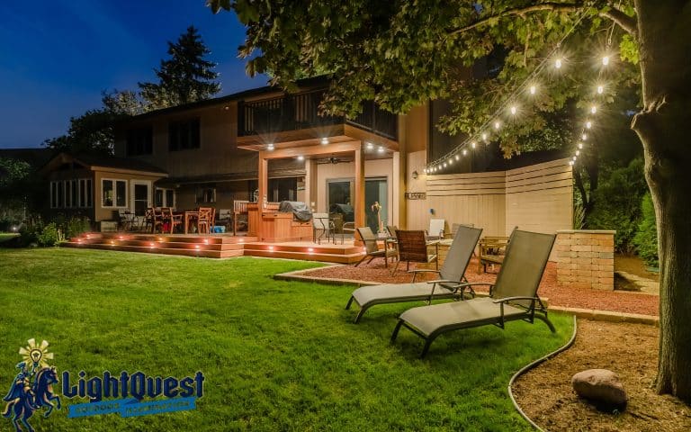 Professionally installed low-voltage landscape lighting illuminating a backyard deck, patio seating area, and steps for safety and outdoor entertaining in Mequon, Wisconsin.