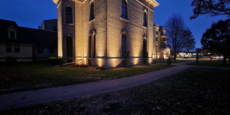 Landscape Lighting Installation in Hartland Custom outdoor lighting design highlighting a historic-style brick building, architectural details, and walkway at night in Lake Forest, Illinois.